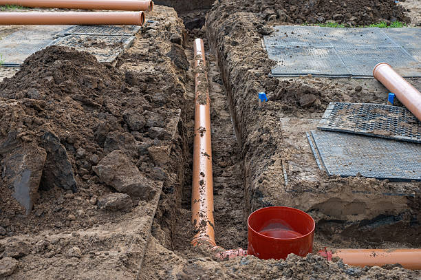 sewer pipe installation in ground trench at residential construction site.